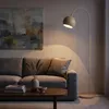 A floor lamp illuminates a living room scene with a sofa and coffee table. Produktbild-Vorschau