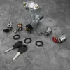 A collection of car ignition switch parts and keys laid out on a textured gray surface. Podgląd zdjęcia produktu