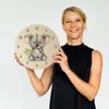 A woman is holding a round clock with a koala illustration. Produktbild-Vorschau