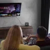 A couple watching TV and eating popcorn, with a media player connected to the TV. Anteprima dell’immagine prodotto