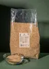 A large bag of puffed quinoa is shown next to a glass bowl filled with quinoa, against a dark green background. Produktbild-Vorschau
