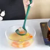 A person is using a green ladle to scoop food from a bowl of soup. Náhled obrázku produktu