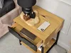 A bedside table with a lamp, candles, and a phone charging. Voir les images du produit