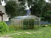 A greenhouse in a backyard setting with plants inside. Produktbild-Vorschau