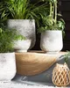 Several planters with plants are arranged on a step, with a woven mat and a lantern. Podgląd zdjęcia produktu