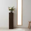 A dark wood pedestal with a floral arrangement on top, placed next to a tall, narrow window. Produktbild-Vorschau