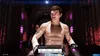 A boxer is shown walking down a tunnel towards the ring, with lights and a crowd visible in the background. Produktbild-Vorschau