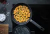 A frying pan with sliced pumpkin and rosemary cooking on a stovetop. Podgląd zdjęcia produktu