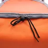 A close-up view of the top of an orange shopping cart bag, showing a drawstring closure with a black plastic toggle. Produktbild-Vorschau