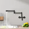 A black wall-mounted kitchen faucet with water flowing into a sink. Podgląd zdjęcia produktu