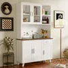 A white sideboard with glass doors and wooden top, decorated with various items like books, a radio, flowers, and artwork on the wall. Podgląd zdjęcia produktu