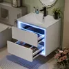 A modern white bathroom vanity with two drawers, illuminated by blue LED lights. The vanity is mounted on the wall and features a white sink and black faucet. Produktbild-Vorschau