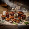 A collection of ceramic fermentation pots and related items are arranged on a burlap cloth, with a wooden barrel and rustic background. Voir les images du produit