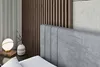 Close-up view of a bed's headboard and a bedside table with a lamp and vase. Produktbild-Vorschau