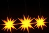 Three illuminated star-shaped lanterns hanging against a black background. Voir les images du produit