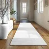 A long white rug is laid out on a wooden floor in a hallway, with a large white planter and a tree branch on the left. Podgląd zdjęcia produktu