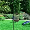 A garden scene with a birdcage on a stand and a lounge chair. Produktbild-Vorschau