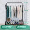 A black metal clothing rack with various items of clothing and shoes displayed on it, set against a patterned wallpaper. Produktbild-Vorschau