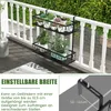 A black metal plant stand with two shelves is hanging on a white railing, with various potted plants on the shelves. The scene is set on a wooden deck with greenery in the background. A smaller inset image shows a close-up of the adjustable hooks. Produktbild-Vorschau