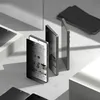 Several smartphones are arranged diagonally on a light gray surface, with shadows cast by overhead lighting. One phone in the foreground has a privacy screen protector partially obscuring its display, which shows a social media feed. Produktbild-Vorschau