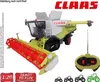 A remote-controlled toy combine harvester, specifically a Claas Lexion 780, is shown from a slightly elevated front-left angle against a white background. A remote control is placed to the right of the toy. Produktbild-Vorschau