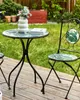 A garden table and chair set with a leaf pattern, set up on a wooden deck in a garden. Náhled obrázku produktu