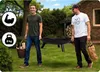 Two men carrying a fire pit in a backyard setting. Náhľad obrázku produktu