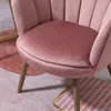 Close-up of a pink velvet chair with wooden legs on a patterned rug. Náhľad obrázku produktu