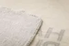 A close-up view of the corner of a light gray blanket with a stitched edge. Produktbild-Vorschau