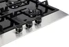 A close-up view of a gas stove top with three control knobs in the foreground. Produktbild-Vorschau