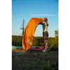 A person is setting up a sleeping bag outdoors in a forest during sunset. Anteprima dell’immagine prodotto