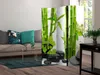 A room divider with a bamboo and stone motif is placed in a living room setting next to a sofa. Podgląd zdjęcia produktu