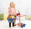A young girl is playing with a toy shopping cart filled with pretend groceries. Produktbild-Vorschau