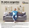 A man relaxing on a couch in a living room, with shelves in the background. Produktbild-Vorschau