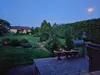 A garden scene at dusk with solar garden lights illuminating a pathway and bushes. Náhled obrázku produktu