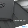 A close-up view of a black tablet case, partially open, revealing a tablet inside. The case has a textured surface and a circular rotating mechanism. Text overlays indicate features and branding. Produktbild-Vorschau