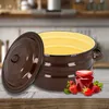 A brown enamel pot with a yellow interior sits on a wooden table, next to a jar of jam and strawberries. Produktbild-Vorschau