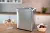 Die Unold Eismaschine Profi Plus 2,5 L steht auf einer Küchentheke neben drei Eistüten auf einem Stä Produktbild-Vorschau