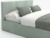 A close-up view of a bed with mint-colored upholstery, white bedding, and gray pillows. Produktbild-Vorschau