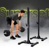 A man is performing a deadlift with a barbell in front of a pair of black squat stands. The background is dark with smoky effects and bright yellow text. Náhľad obrázku produktu