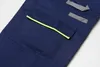 A close-up view of a navy blue work pant pocket with yellow trim and gray reflective accents. Produktbild-Vorschau