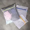 Three mesh laundry bags with zippers are laid out on a gray surface. Voir les images du produit