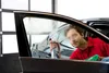 A man is cleaning the inside of a car window with a spray bottle and a cloth. Produktbild-Vorschau