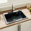 A black kitchen sink with a faucet and soap dispenser, placed on a wooden countertop. Dimensions are marked with a ruler. Produktbild-Vorschau