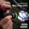A hand holding a small black flashlight with a green band, with bicycle handlebars in the background. Podgląd zdjęcia produktu