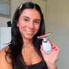 A woman is holding a white facial toning device with a silver and red LED light. Náhľad obrázku produktu
