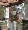An outdoor porch with a hanging lantern, railing, and chair, with trees and a house in the background. Náhled obrázku produktu