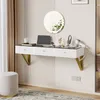 A modern white floating vanity table with gold accents, a round mirror, and various beauty products arranged on top, set against a textured wall. Voir les images du produit