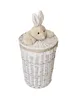 A white wicker laundry basket with a lid and a plush bunny toy on top. Produktbild-Vorschau