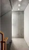 A modern interior hallway with concrete walls and ceiling, featuring a wooden handrail for stairs and three white LED ceiling lights. Produktbild-Vorschau